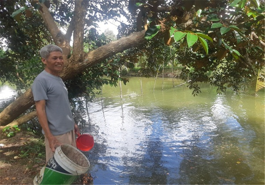 Ảnh: Chú Nguyễn Văn Hiện bên ao nuôi cá của mình